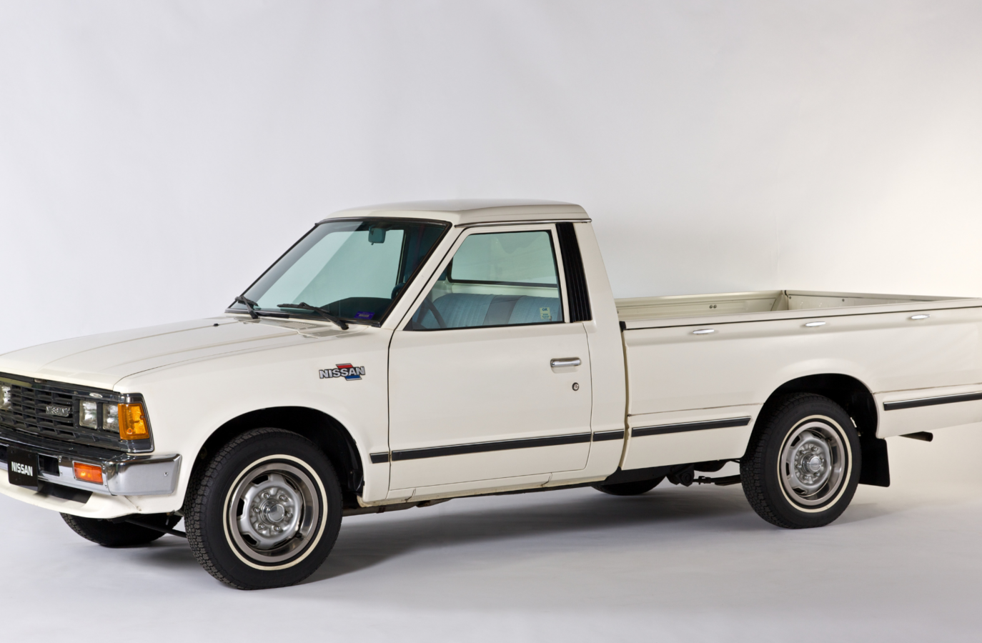 The first Nissan vehicle, a white pickup truck, manufactured in the United States is on display against a white backdrop