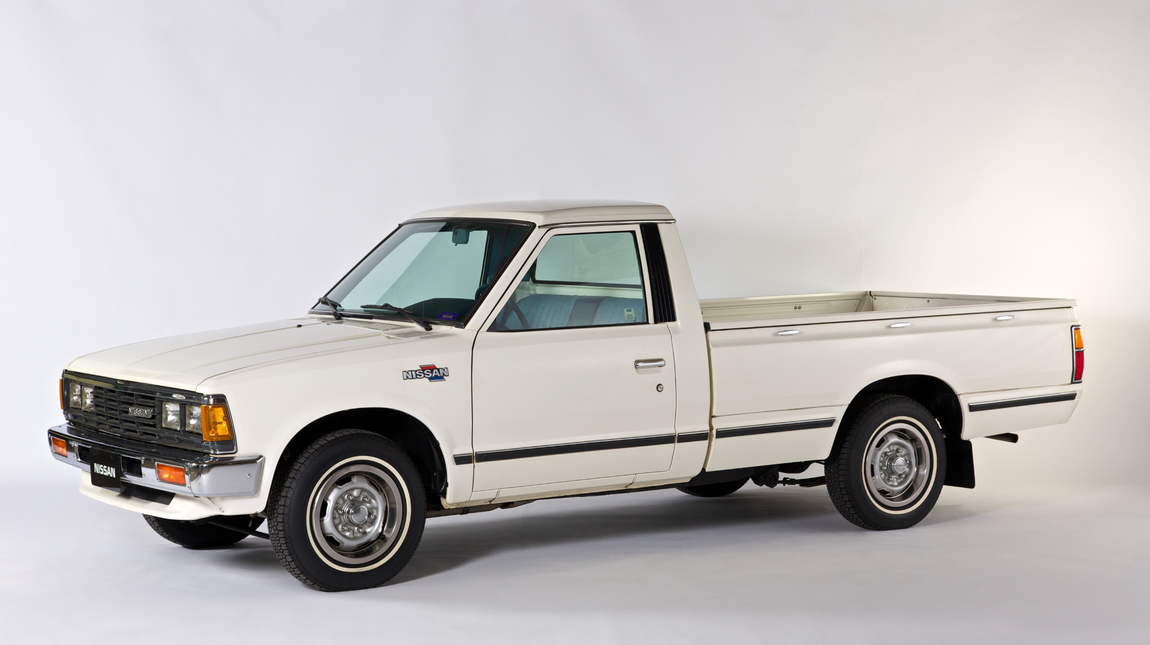 The first Nissan vehicle, a white pickup truck, manufactured in the United States is on display against a white backdrop